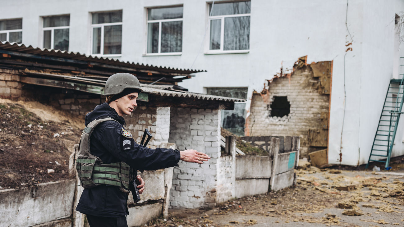 Un policía da instrucciones frente a una guardería donde hoy ha impactado un proyectil, a 17 de febrero de 2022, en Stanitsa Luganska, Oblast de Lugansk (Ucrania)
