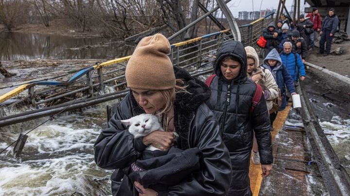Una mujer con su gato cruza un puente destruido mientras los residentes huyen desde el frente de la ciudad de Irpín / EFE