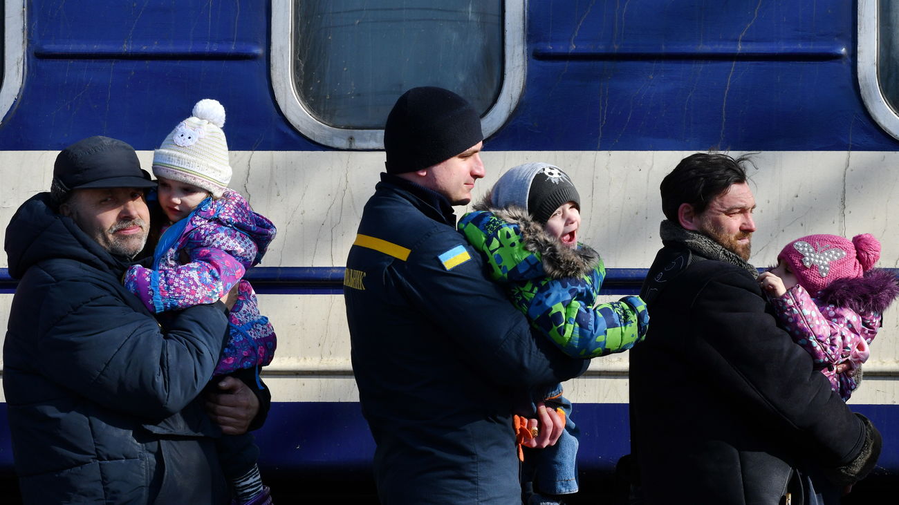 Hombres en Ucrania llevando en brazos a niños para ser evacuados