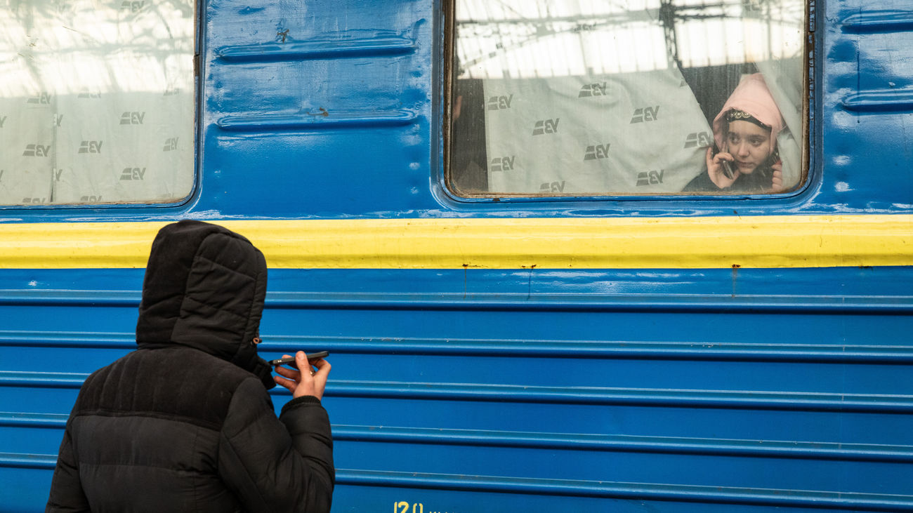 Un hombre hablando con su novia por teléfono mientras sube en Levandivka a un tren hacia Polonia