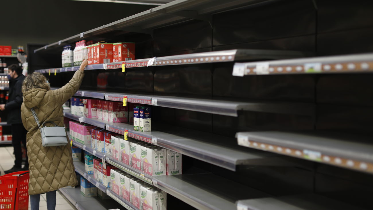 Una mujer frente a la estantería de leche que le faltan algunos productos, en un supermercado Carrefour de Madrid