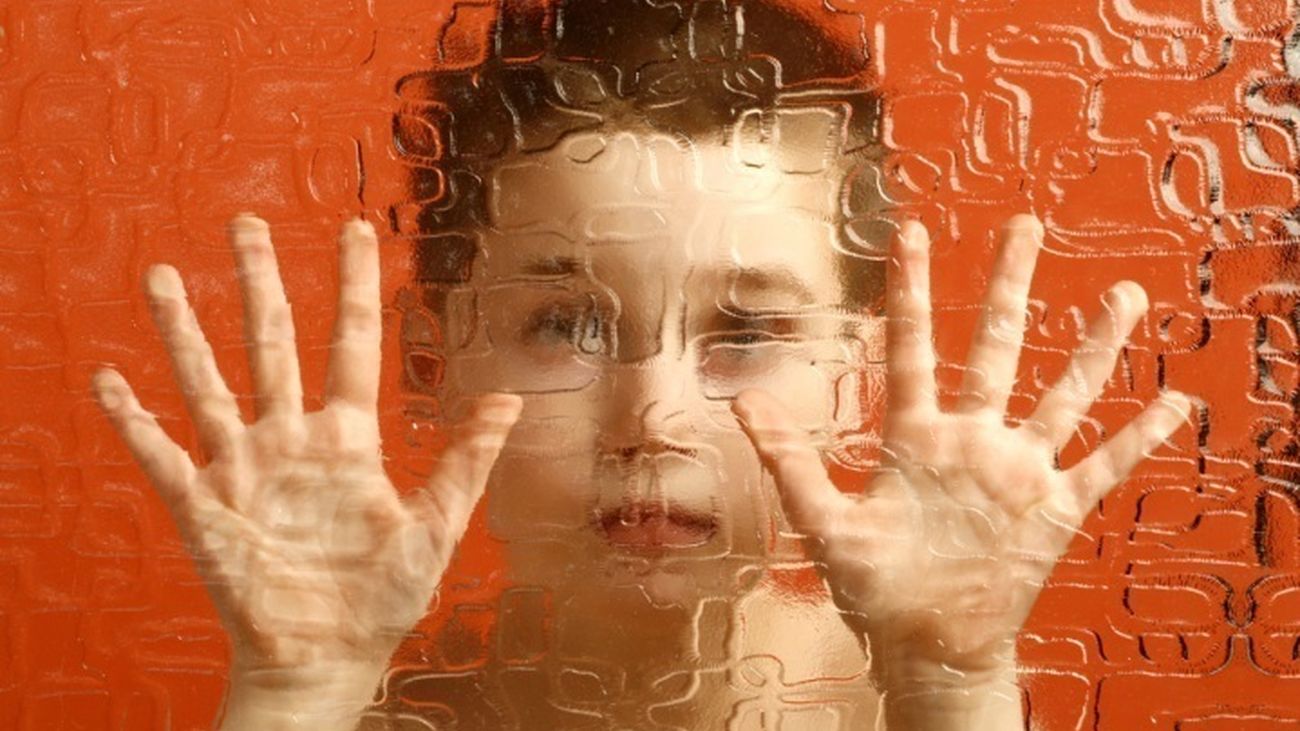 Un niño mira a través de un cristal