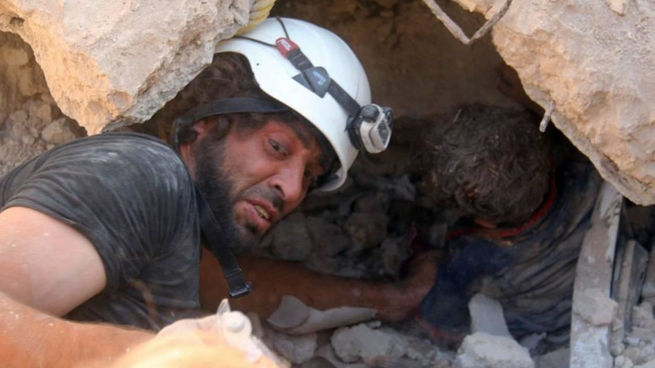 Un casco blanco sirio auxilia a una persona bajo los escombros durante una operación en 2017