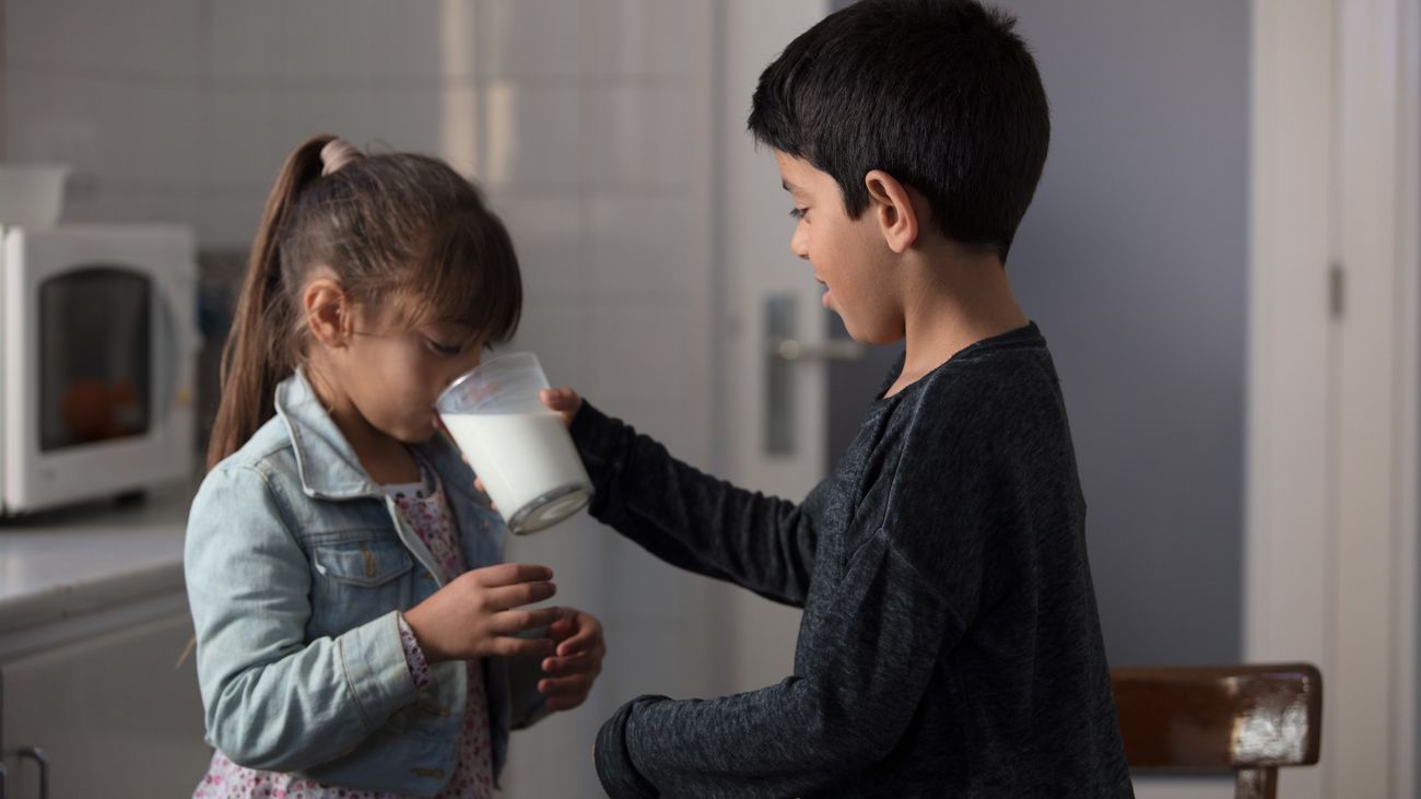 Dos menores comparten un vaso de leche
