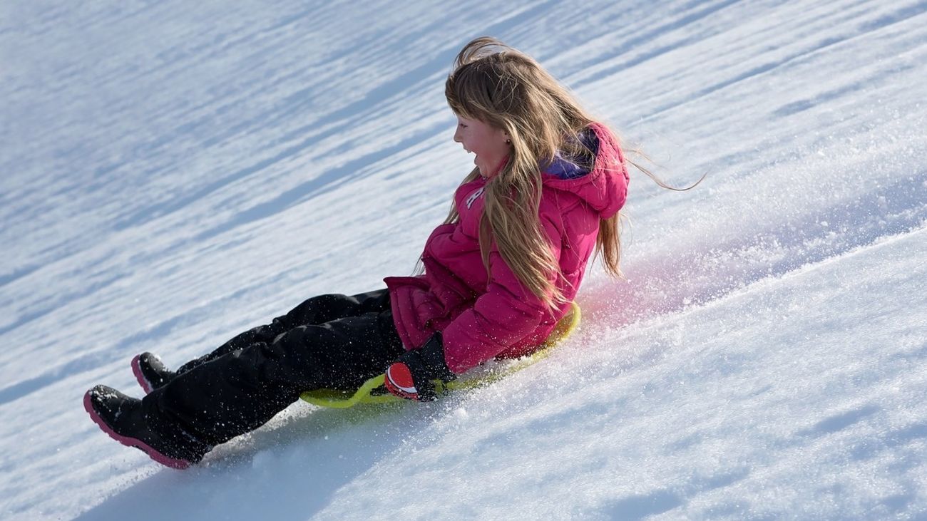 Una chica deslizándose por una pista de nieve