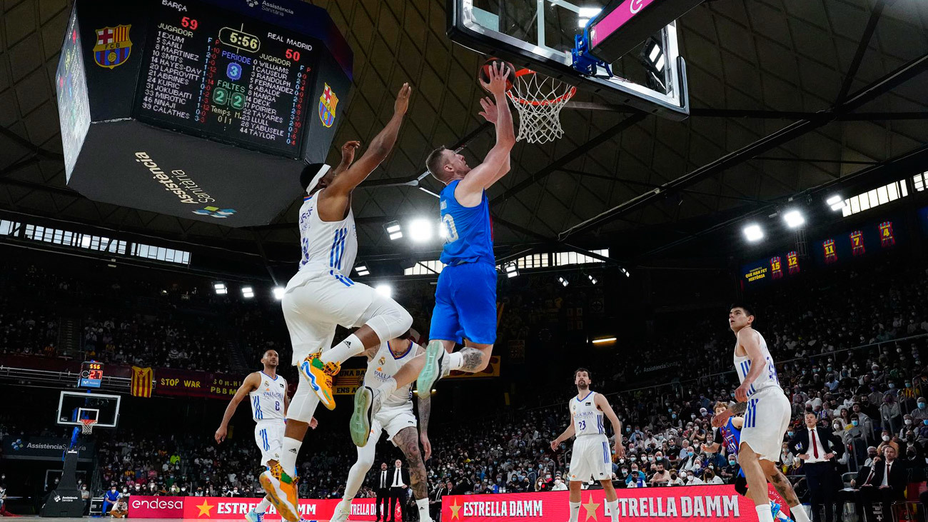 El ala-pívot letón del Barcelona Roland Smits (c) anota ante Yabusele (i) y Deck (d) , del Real Madrid, durante el partido de la Liga Endesa que disputan Barcelona y Real Madrid este domingo en el pabellón Palau Blaugrana