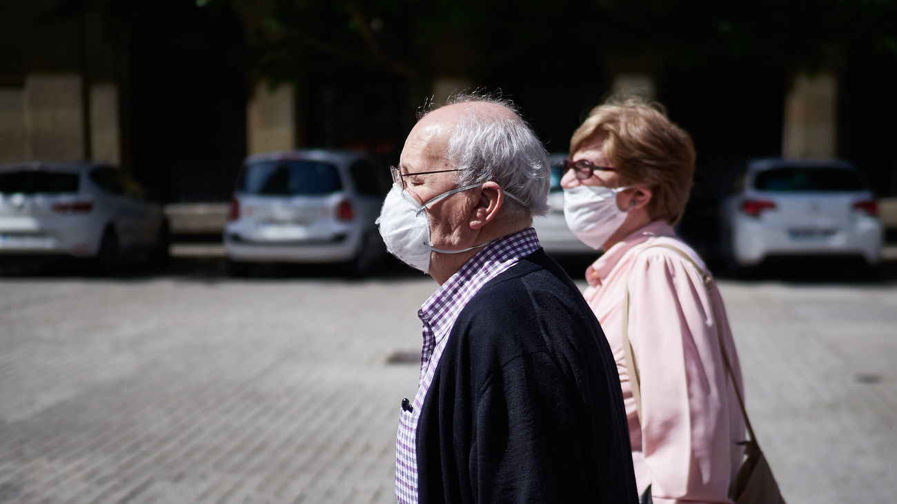 Una pareja de personas mayores camina por la calle con mascarillas