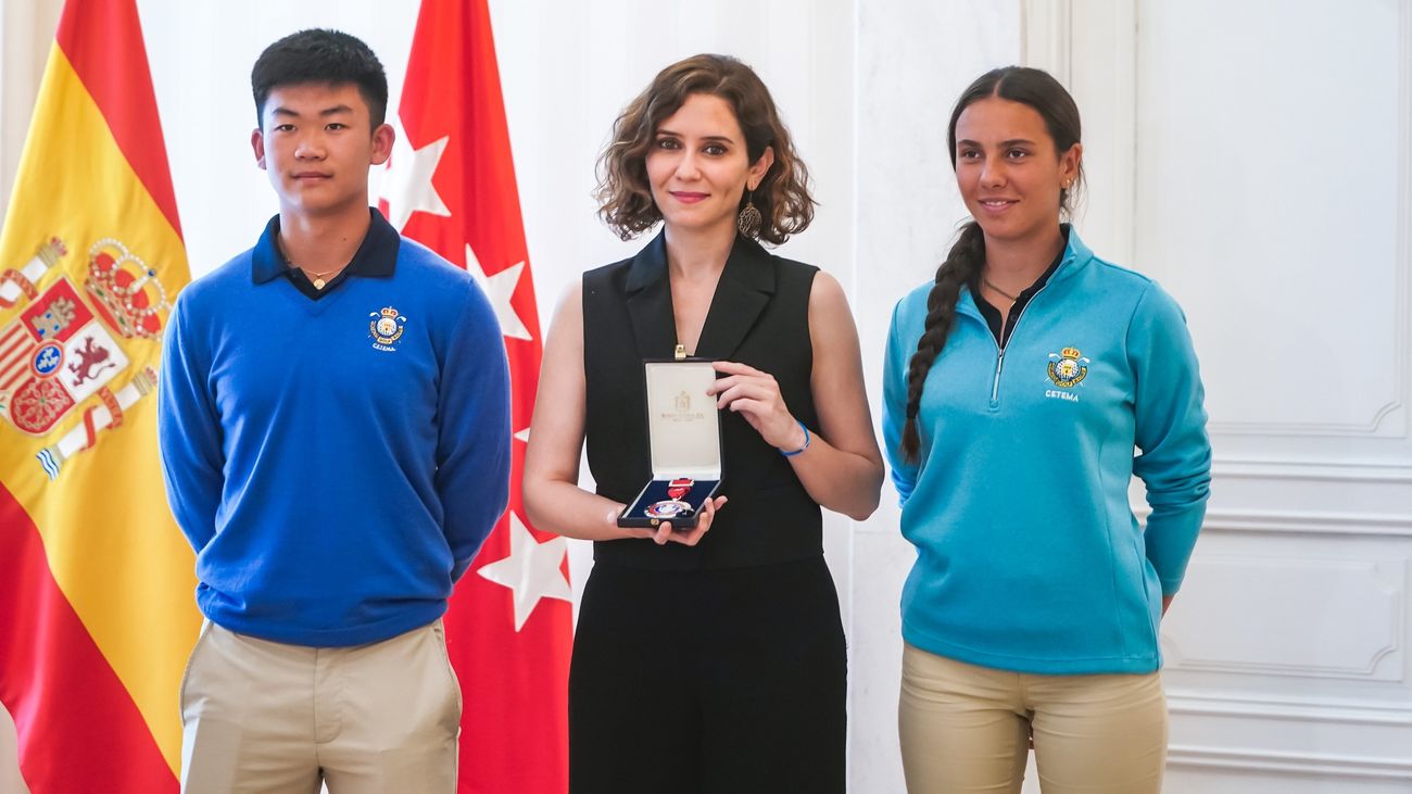 Isabel Díaz Ayudo acompañada por dos jugadores de golf madrileños