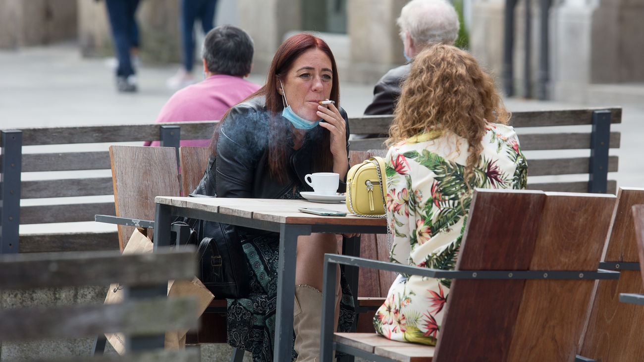 Una mujer fuma en una terraza