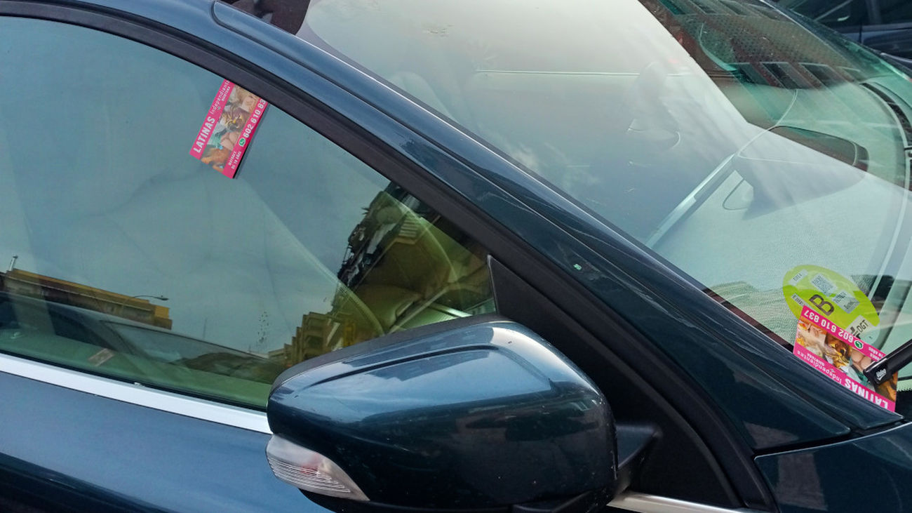 Un coche con varias tarjetas de anuncios de prostitución