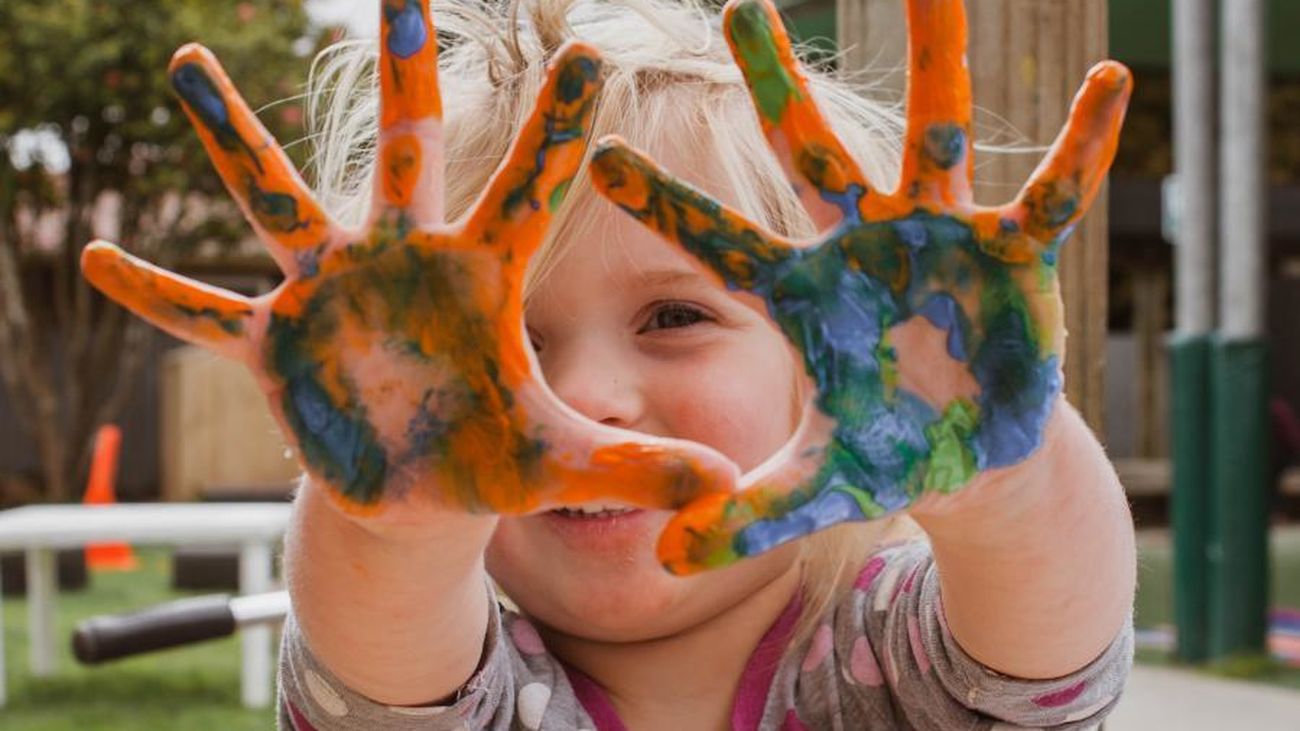 Una niña muestra sus manos llenas de pintura tras una actividad infantil