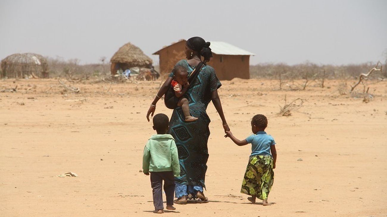 Mujer caminando con sus hijos cerca de una aldea