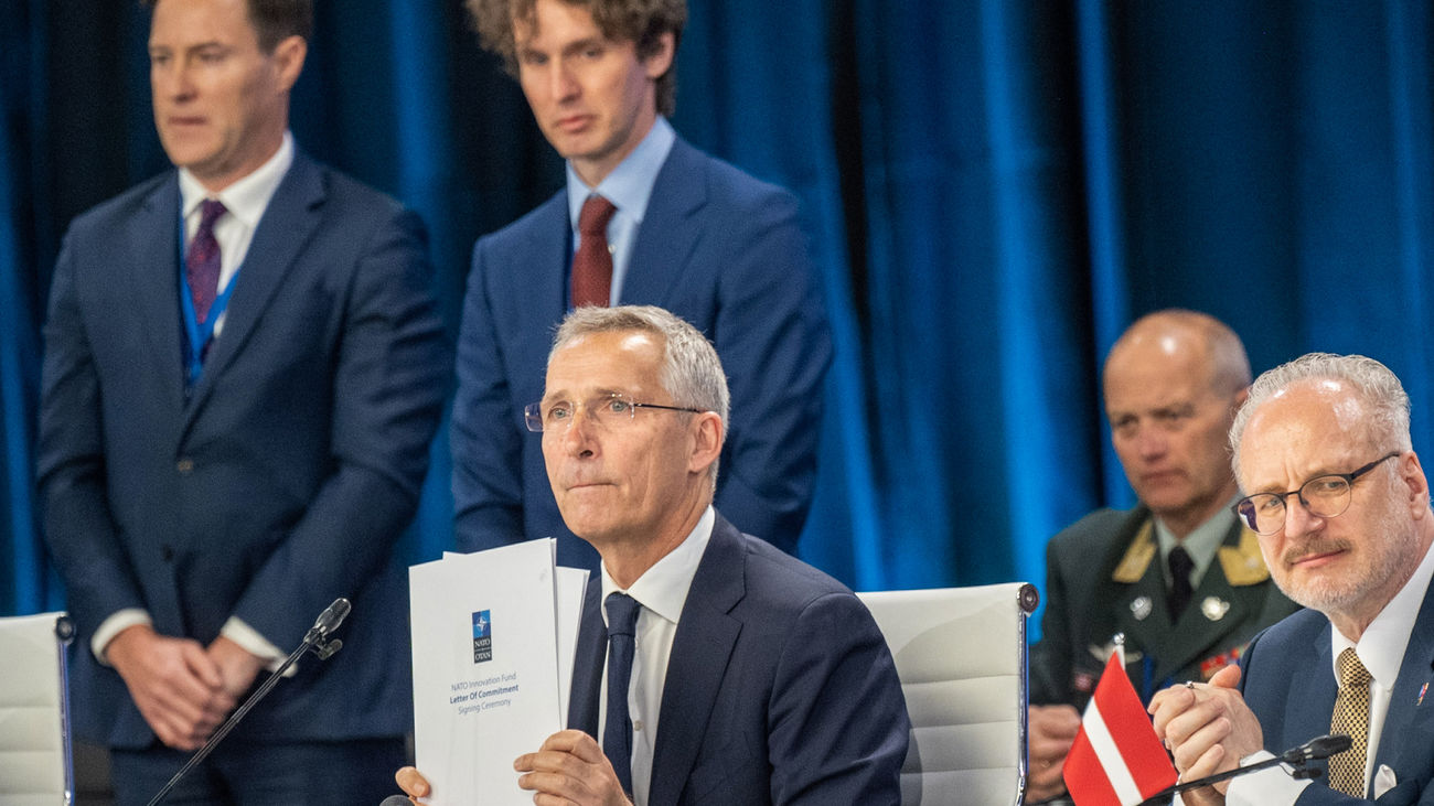 El Secretario General de la OTAN, Jens Stoltenberg (C), sostiene la Carta de compromiso del Fondo de Innovación de la OTAN durante la ceremonia de firma.
