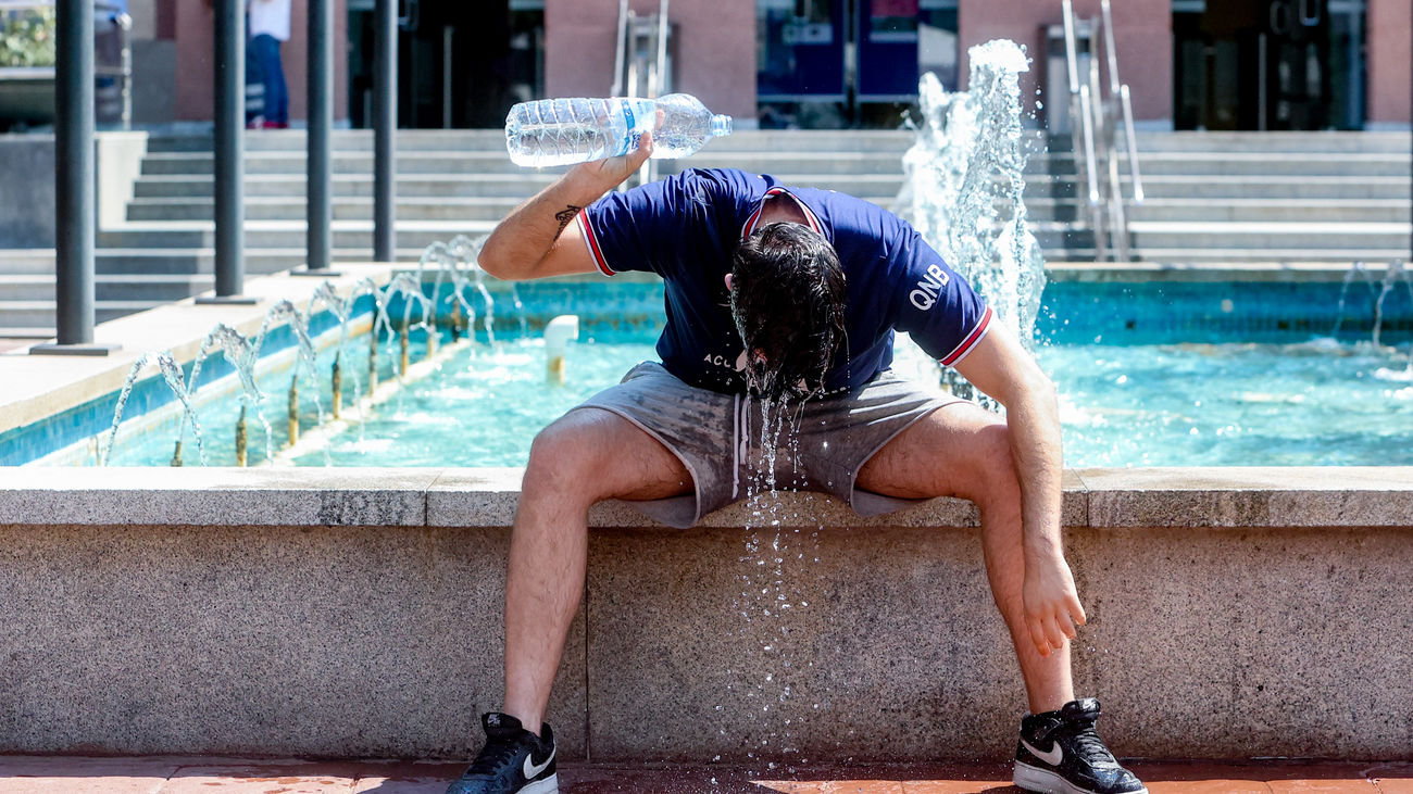 Un joven se refresca en una fuente por la ola de calor