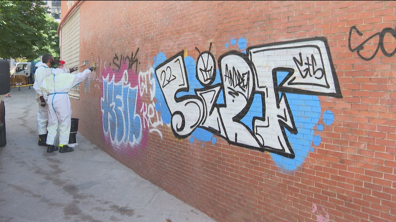 Operarios de limpieza eliminan un grafiti en una pared