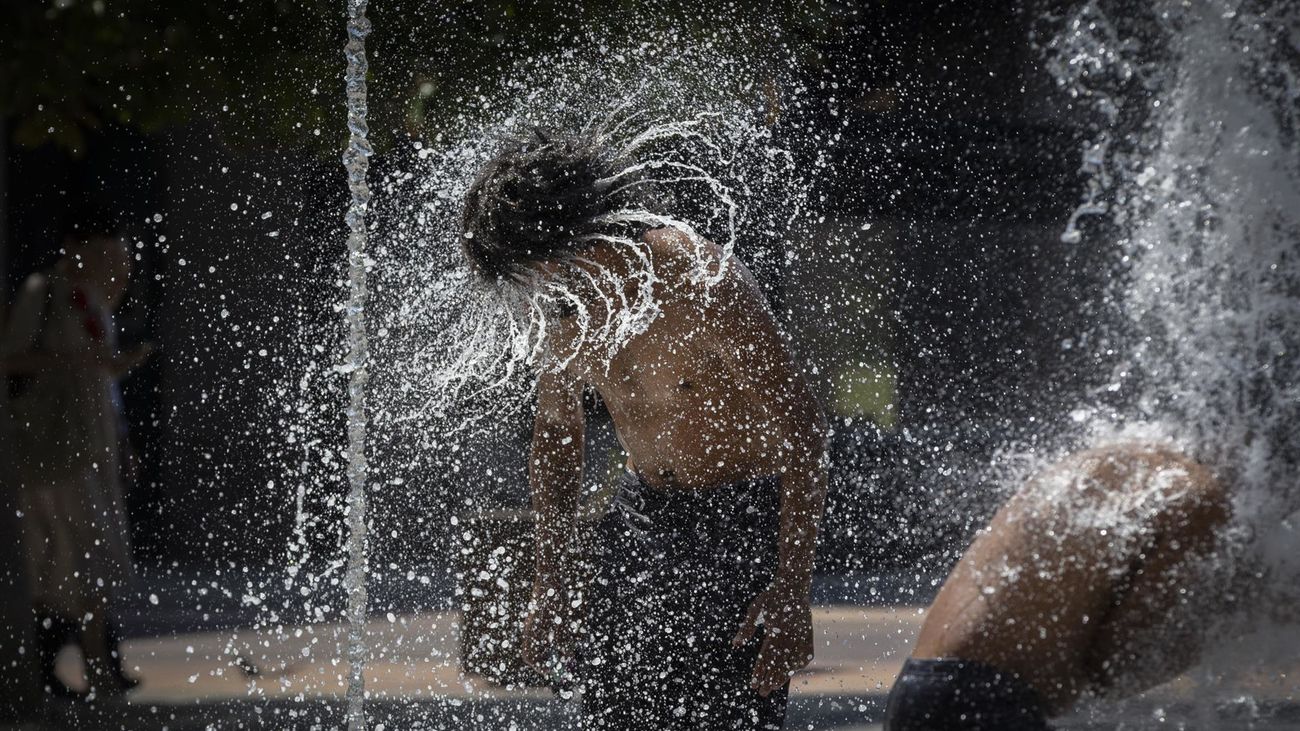 Dos hombres se refrescan en una fuente