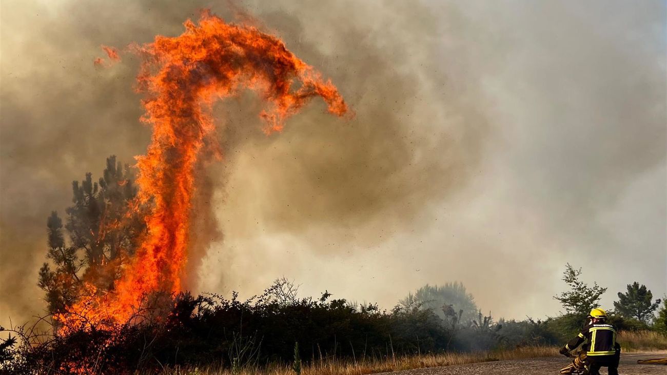 Efectivos de bomberos trabajan en la extinción de un incendio forestal en la carretera N120, en A Cañiza (Pontevedra)