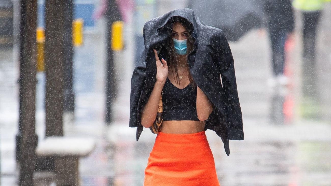 Una mujer se resguarda de la lluvia bajo una chaqueta