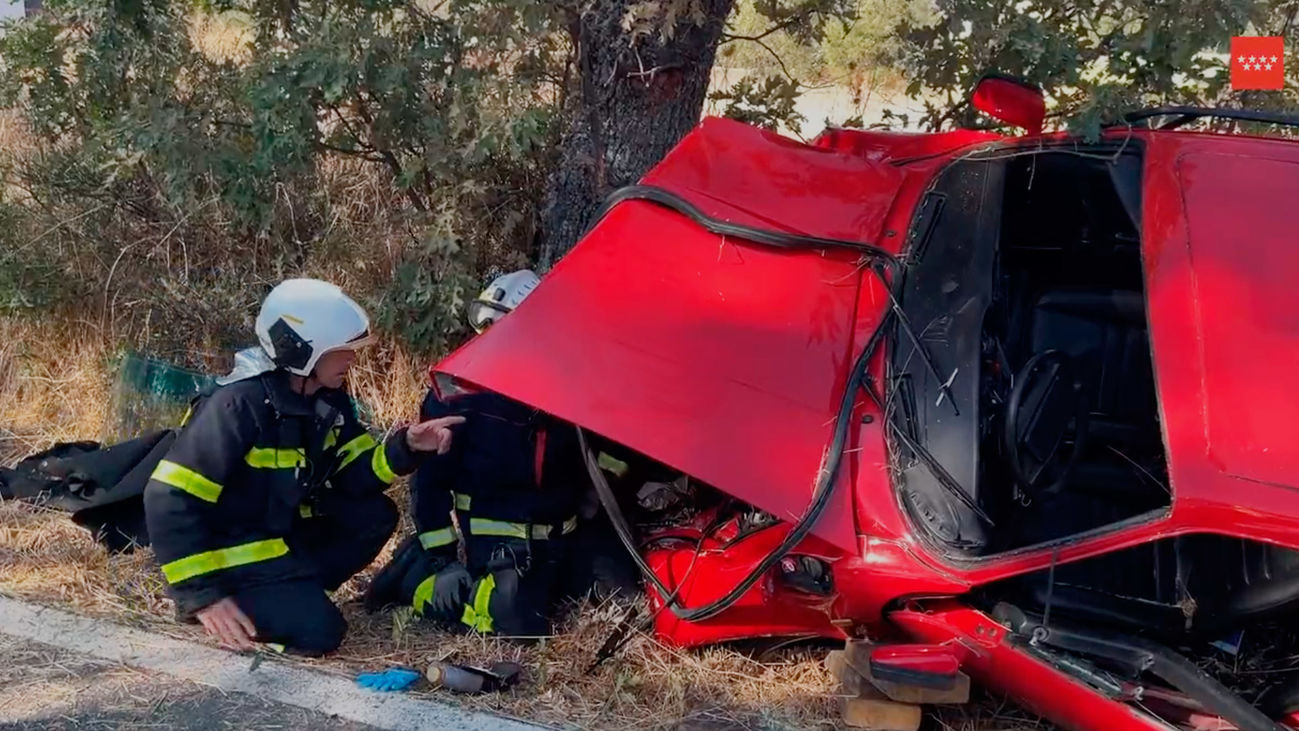 Bomberos de Madrid trabajan para retirar un coche en la M-626, en Miraflores de la Sierra