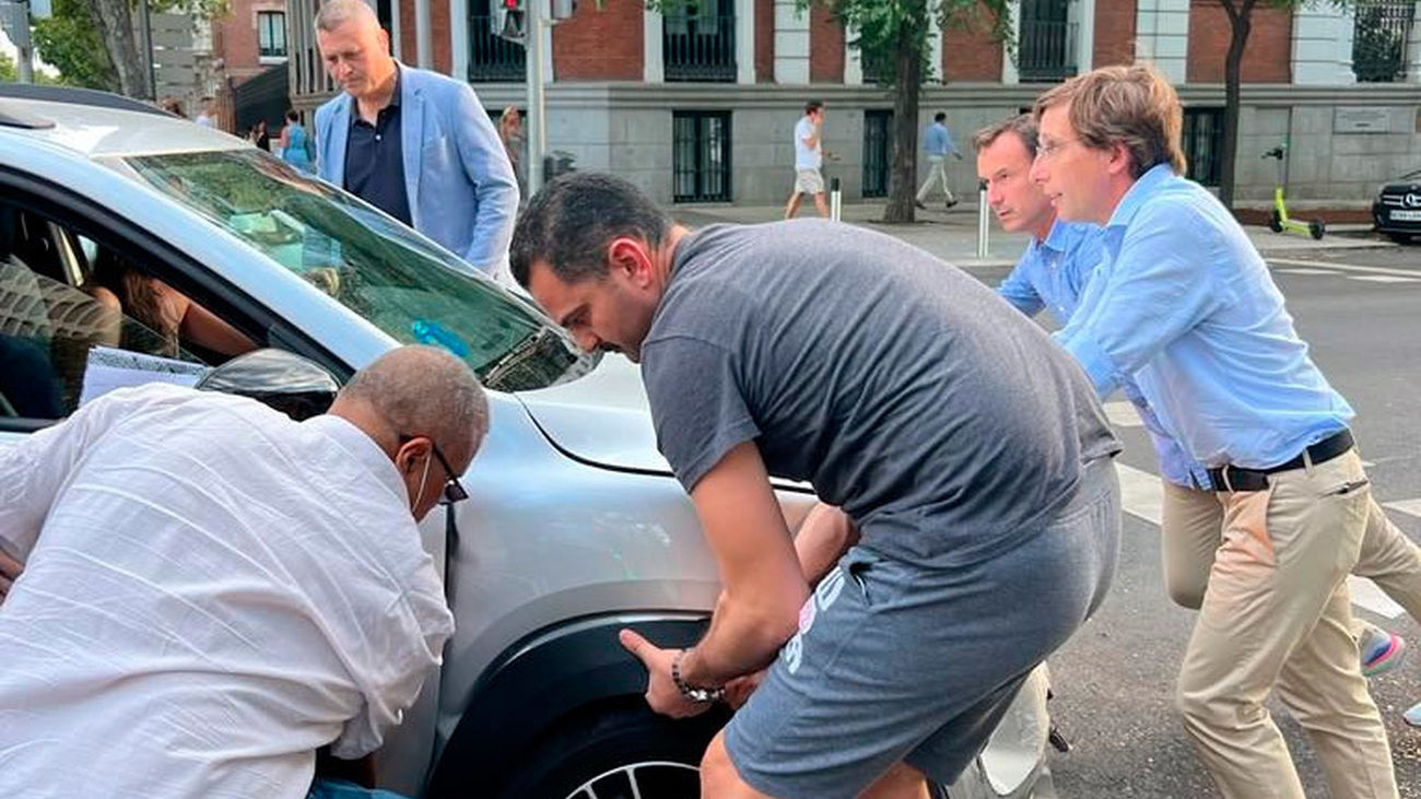 El alcalde de Madrid, José Luis Martínez-Almeida,  empuja un coche accidentado en la calle Velázquez junto a un grupo de transeúntes