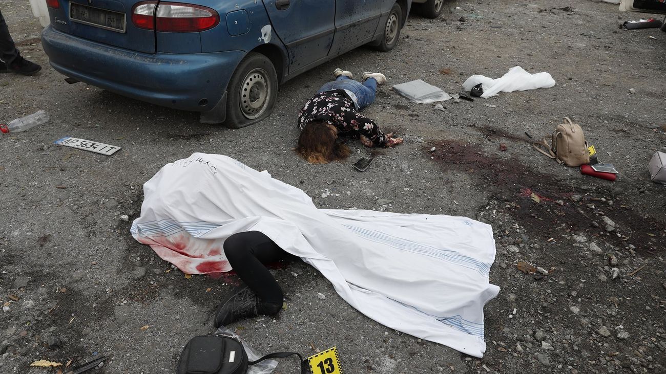 Dos cadáveres yacen en el suelo tras el ataque con misiles rusos perpetrado este viernes en Zaporiyia, Ucrania.