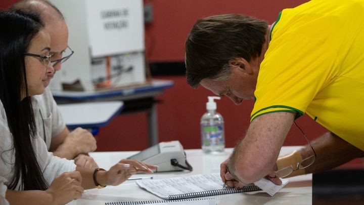 El presidente brasileño Jair Bolsonaro firma su registro ante de votar hoy, en un puesto de votación en Río de Janeiro (Brasil) / EFE