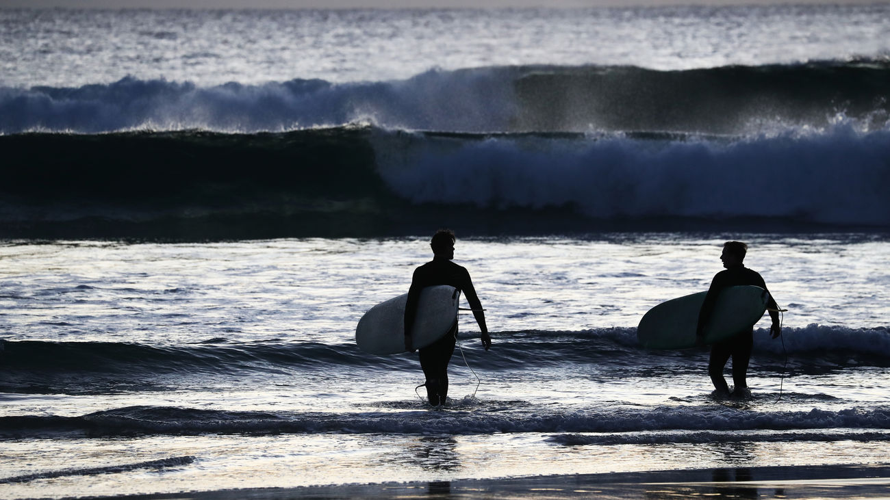 Imagen de dos surfistas en una playa