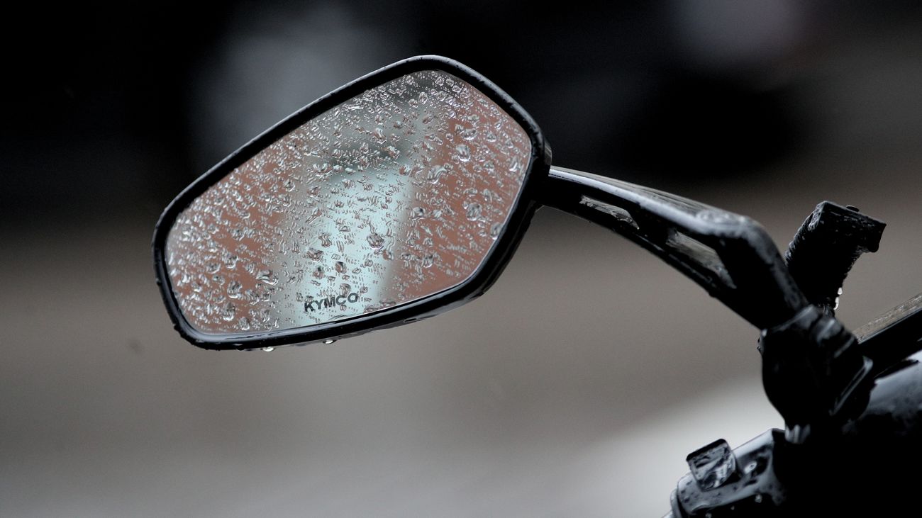 El espejo de una moto, mojado por agua de lluvia