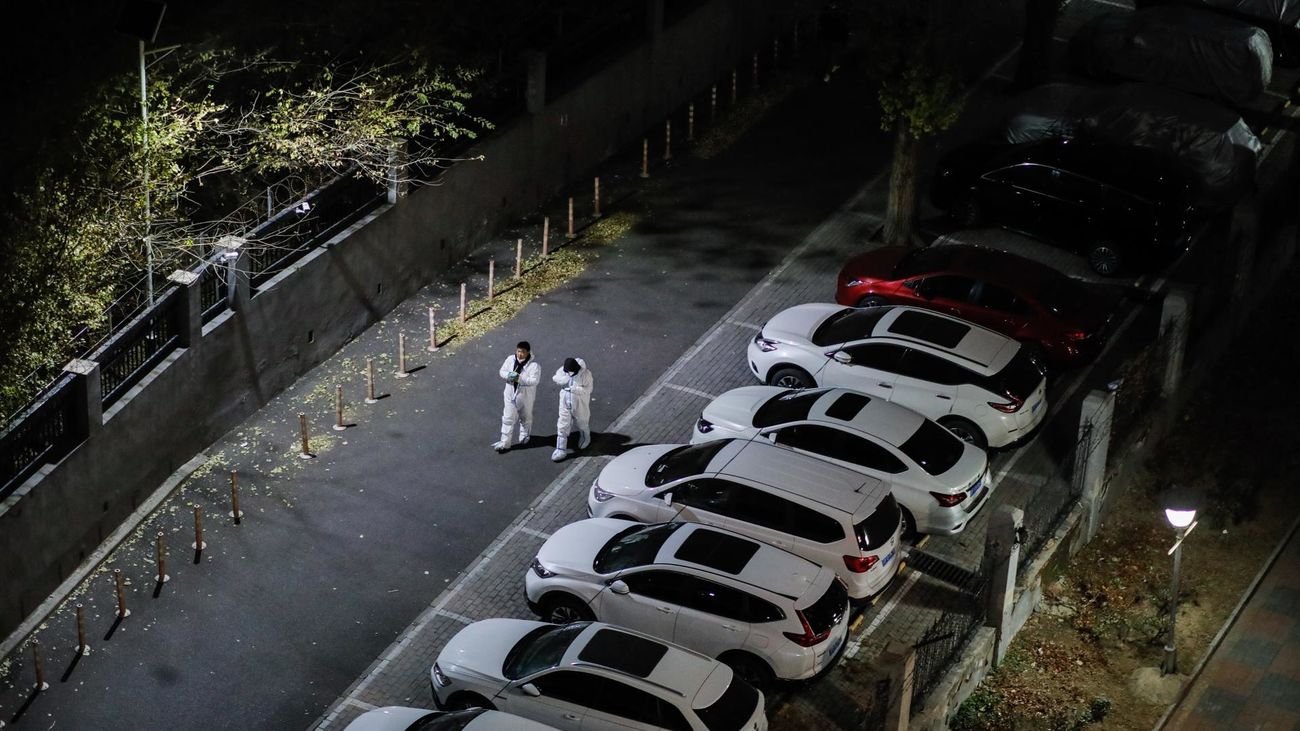 Dos voluntarios caminan por las afueras de un edificio con casos confirmados de covid en  Beijing, China,