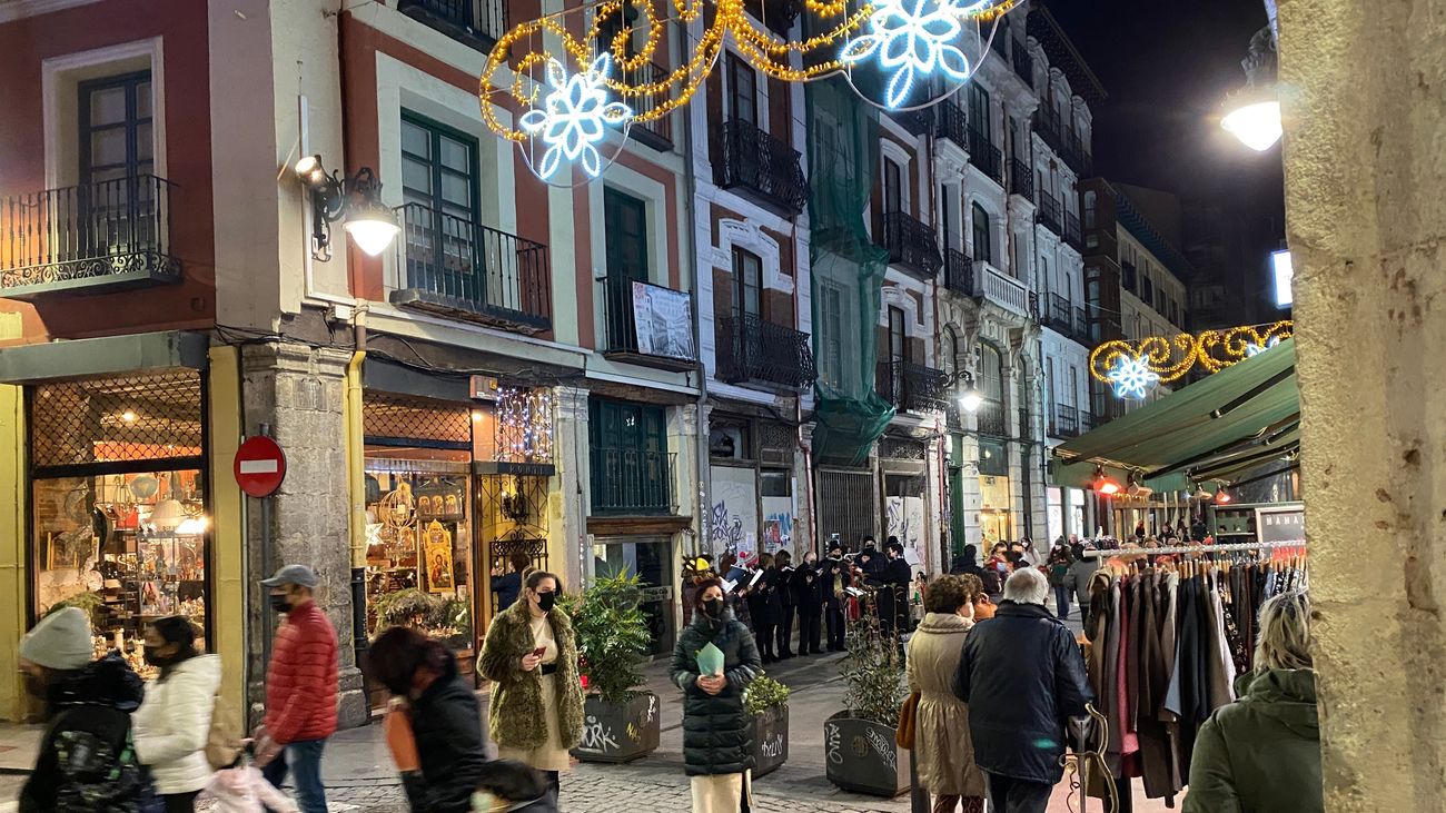 Varias personas caminan por una calle iluminada con luces de Navidad