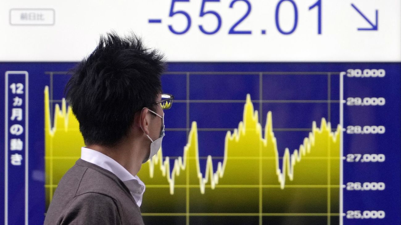 Un transeúnte pasa frente a un panel indicador del mercado de valores en Tokio