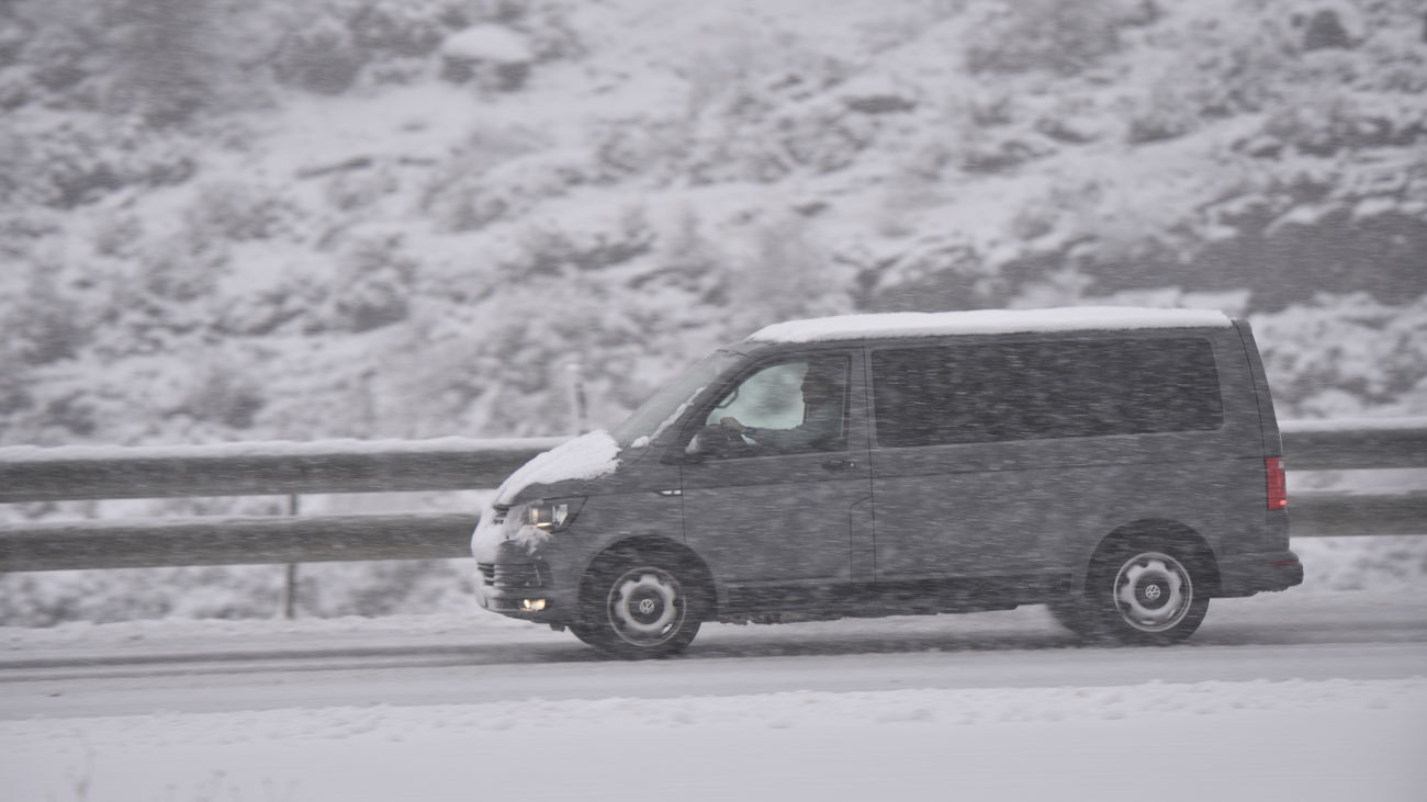 Un coche circula por una carretera nevada