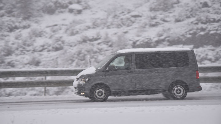 Un coche circula por una carretera nevada