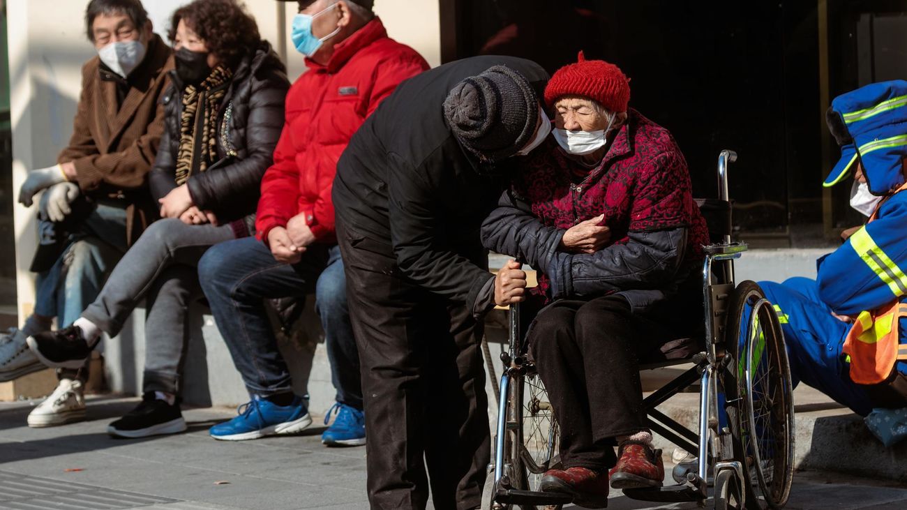 Personas mayores sentadas para disfrutar del sol en la calle, en Shanghai, China
