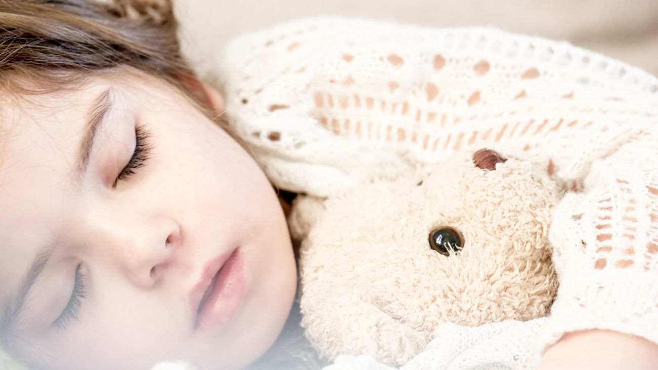 Una niña durmiendo con su osito de peluche