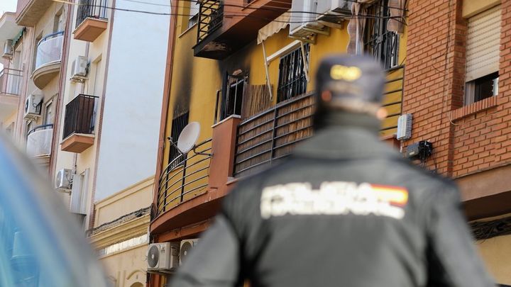 Un agende de Policía Nacional miran en dirección a la vivienda que ha sufrido el incendio en Huelva. / EUROPA PRESS