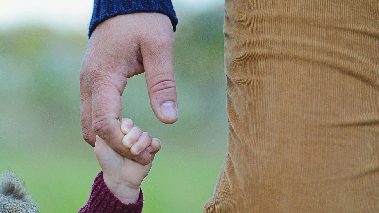 Un niño agarra la mano de su padre