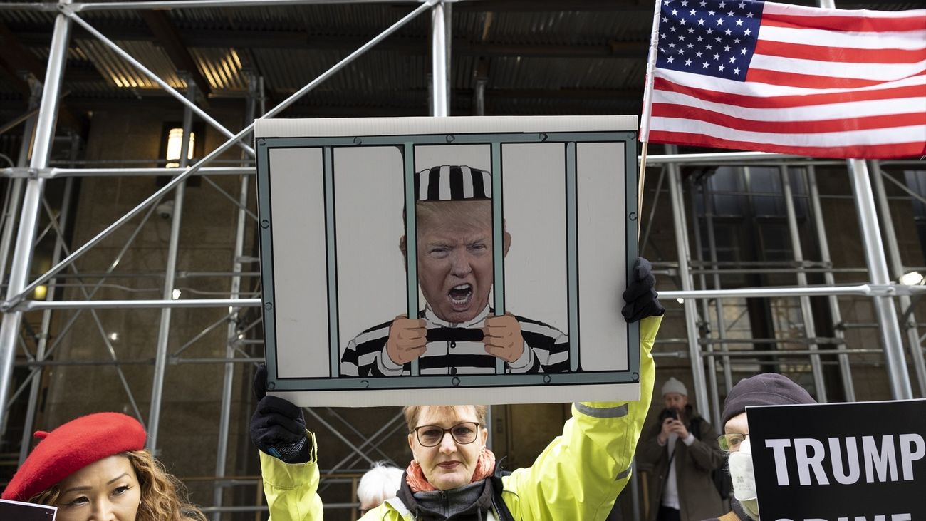 Una manifestante en Nueva York sostiene un cartel con la caricatura de Donald Trump como un preso