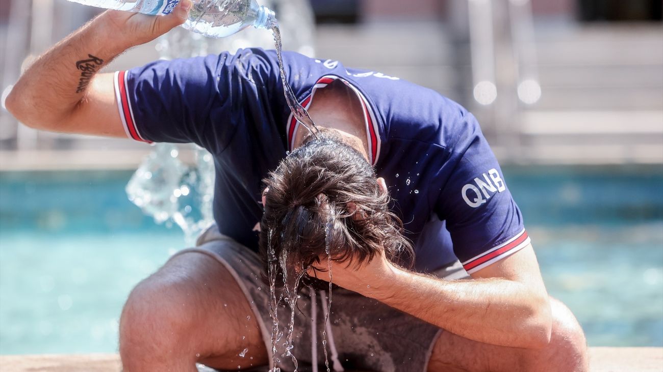 Un joven se tira una botella de agua por encima para combatir la segunda ola de calor en Madrid, en verano de 2022