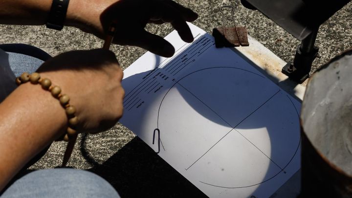 Un especialista de la oficina meteorológica ve un eclipse solar híbrido parcial reflejado en una hoja de datos con el uso de un telescopio en un observatorio astronómico en Quezon City, Metro Manila, Filipinas, el 20 de abril de 2023 / EFE