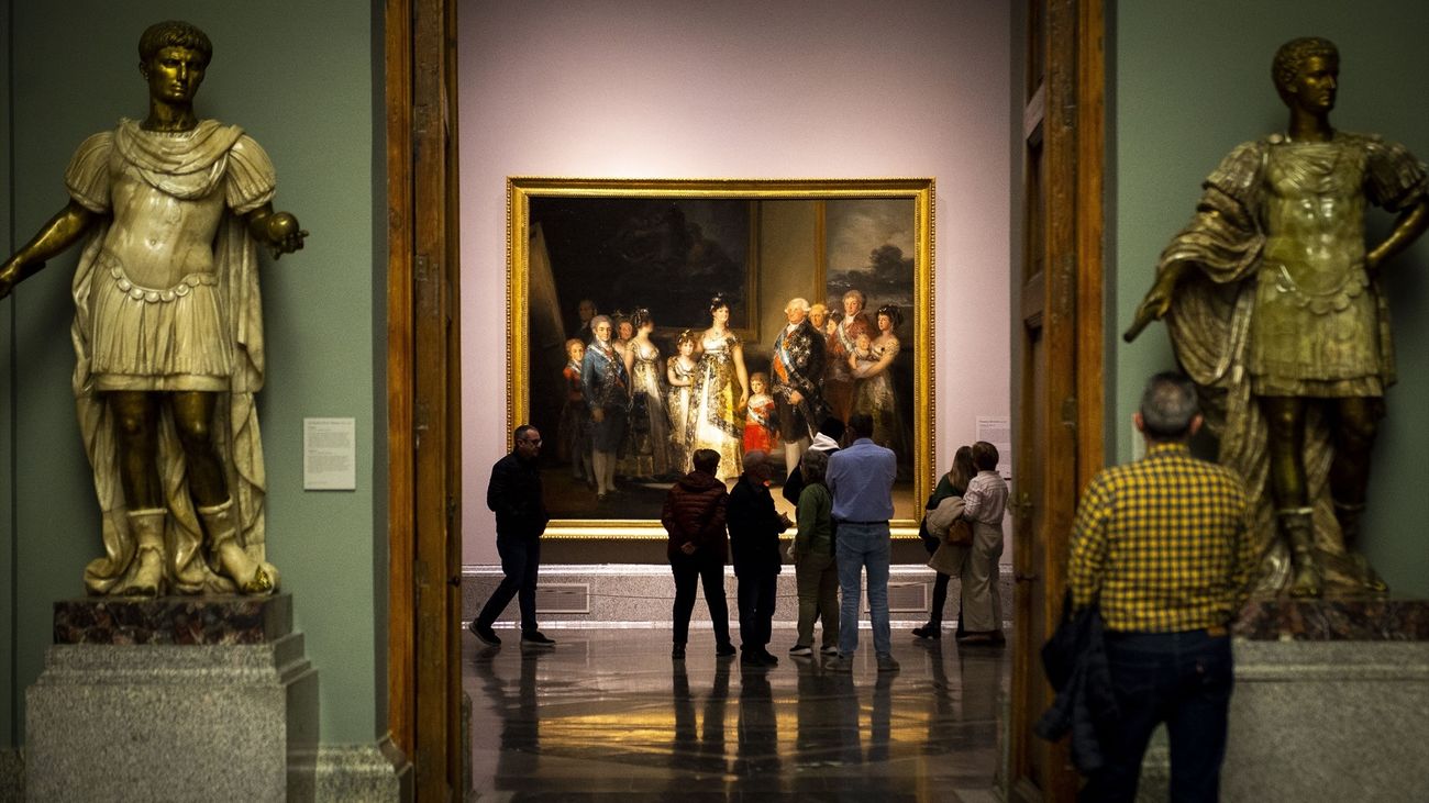 Varias personas observan el cuadro de la familia de Carlos IV de Goya en el Museo del Prado de noche