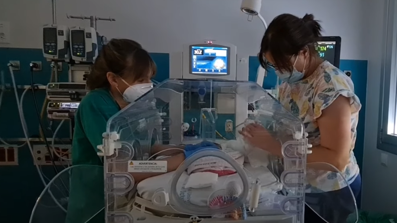 Una enfermera y la madre atienden a un bebé en una incubadora