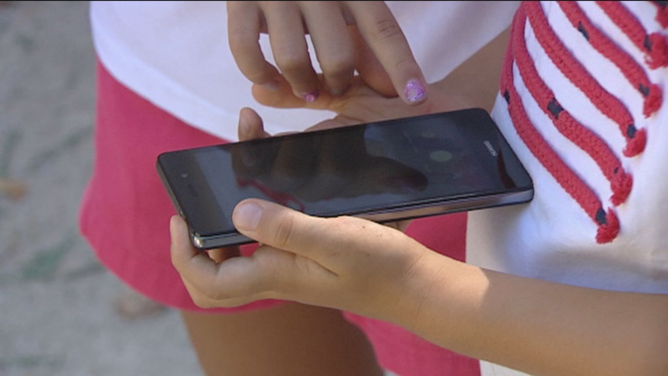 Unos menores utilizan un teléfono móvil