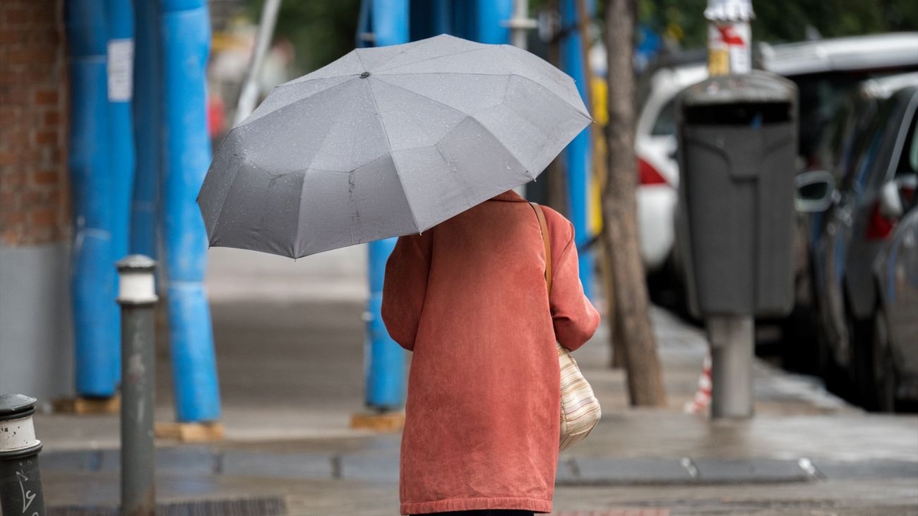 Una mujer camina bajo su paraguas por una calle de Madrid