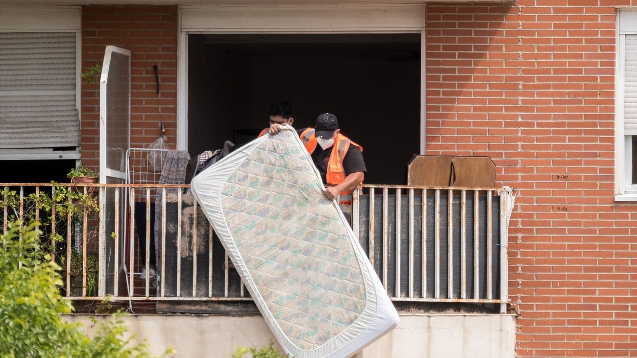 Un trabajador saca un colchón por el balcón durante el desalojo de 60 familias en Alcobendas