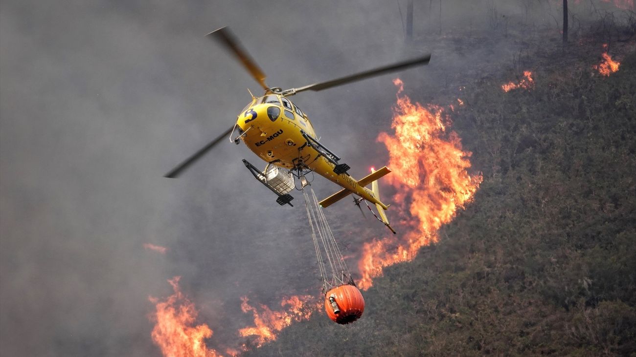 Un helicóptero trabaja para extinguir las llamas en un incendio forestal, a 28 de marzo de 2023, en Toraño, Parres, Asturias