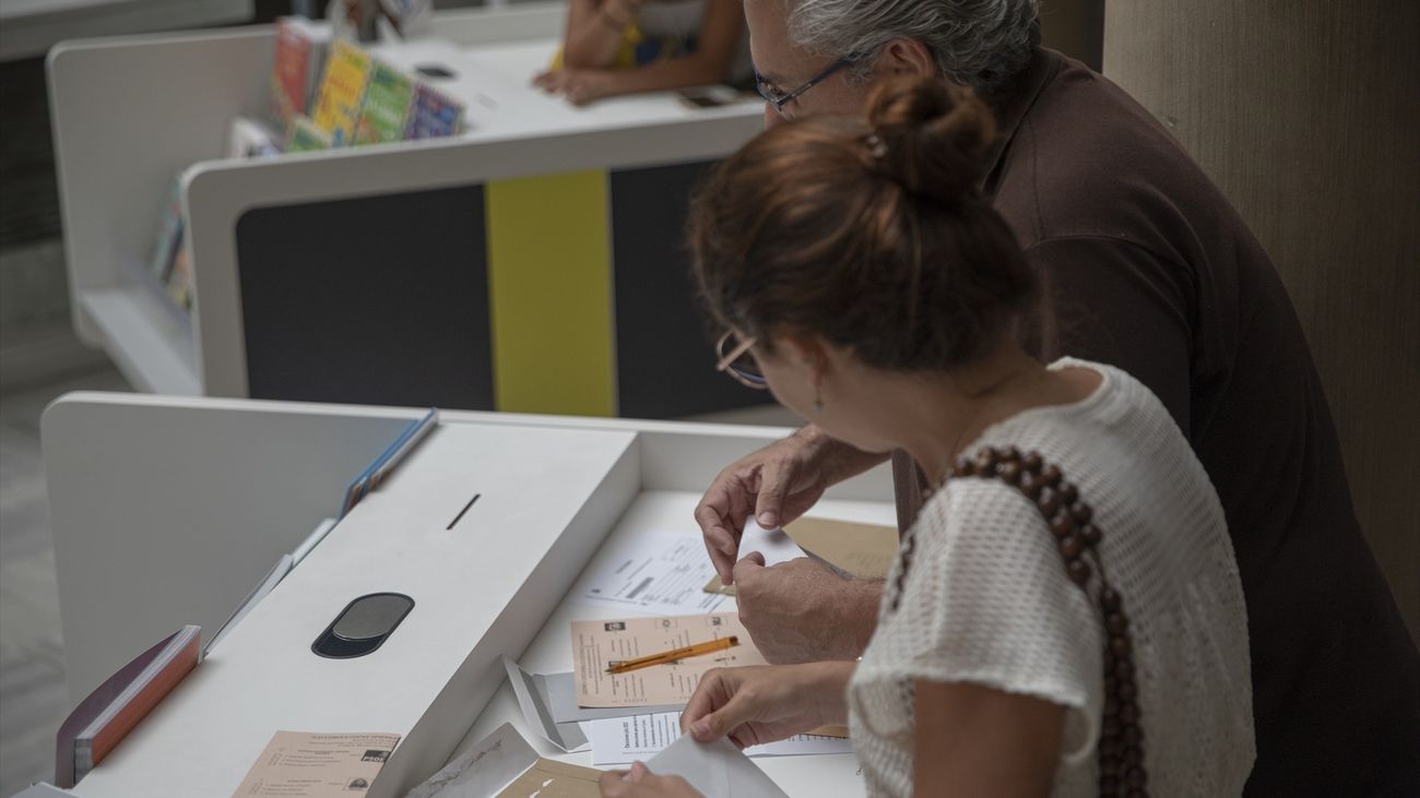 Dos personas depositando su voto por correo