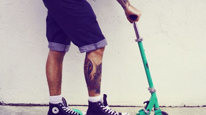 Joven montando en patinete con tatuajes / Archivo