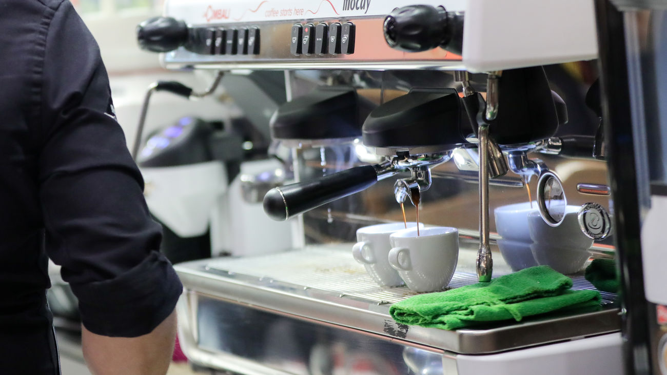 Un camarero prepara café e un bar de Madrid