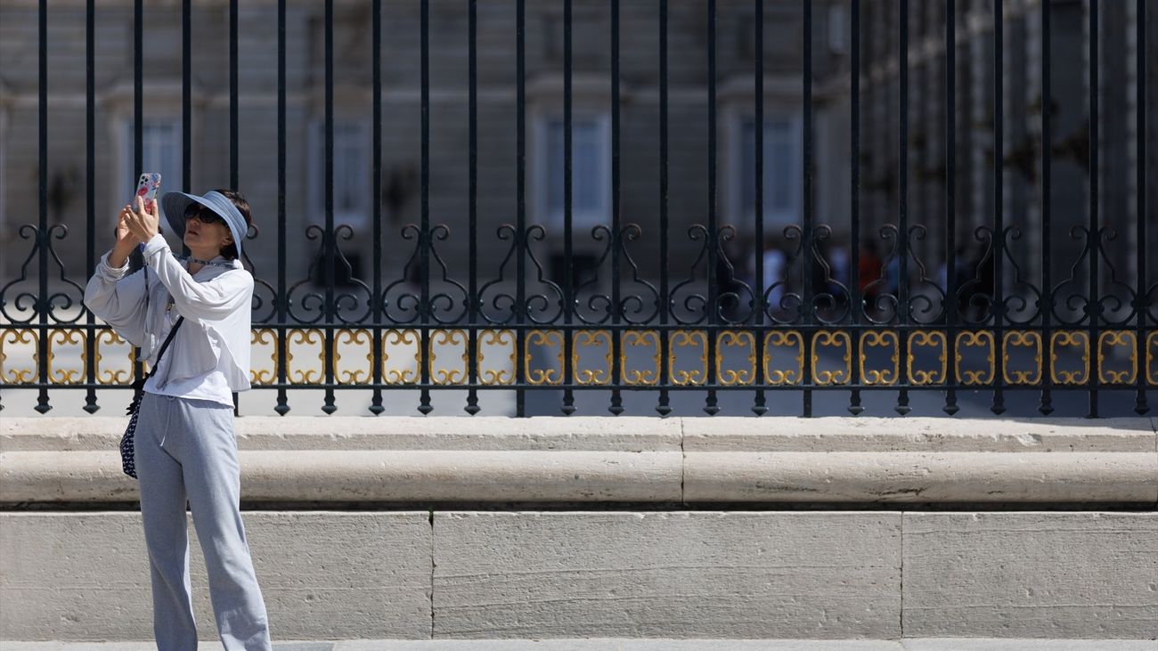 Una turista tomando fotografías frente al Palacio Real de Madrid
